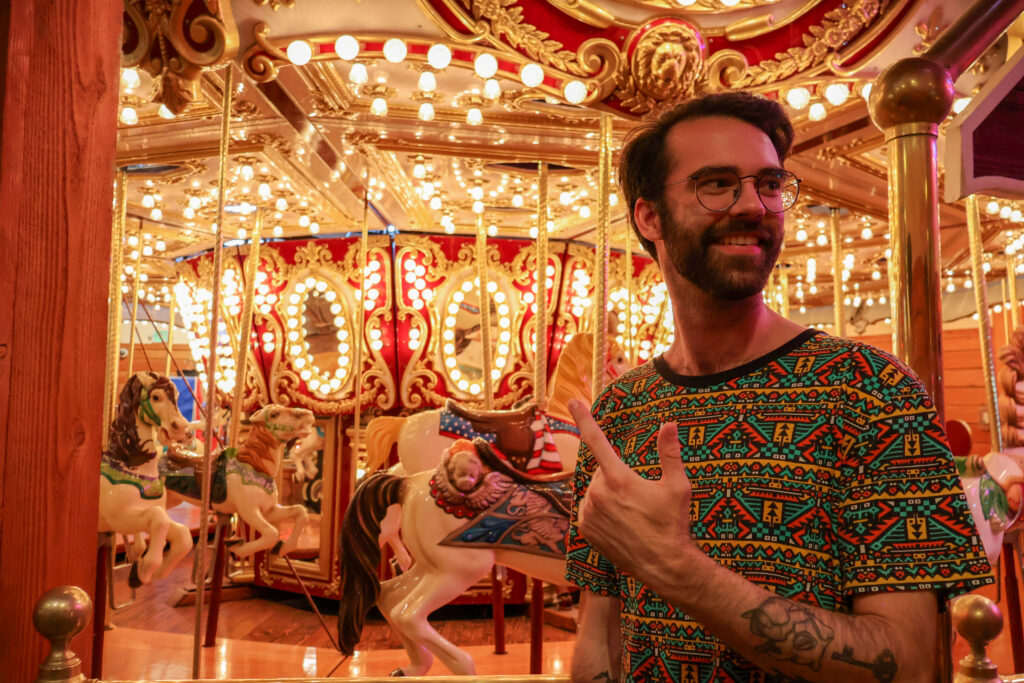 A friend in front of a carnival-style carousel.