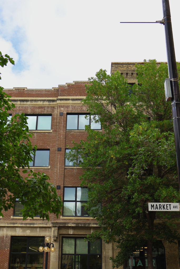 A red brick building covered by trees in Downtown Winnipeg.